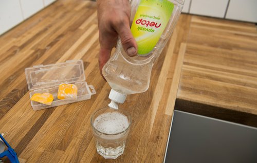 Opvaskemiddel sprøjtes ned i et glas med vand